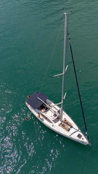 A sailboat with a mast and sails, anchored in turquoise water. 3