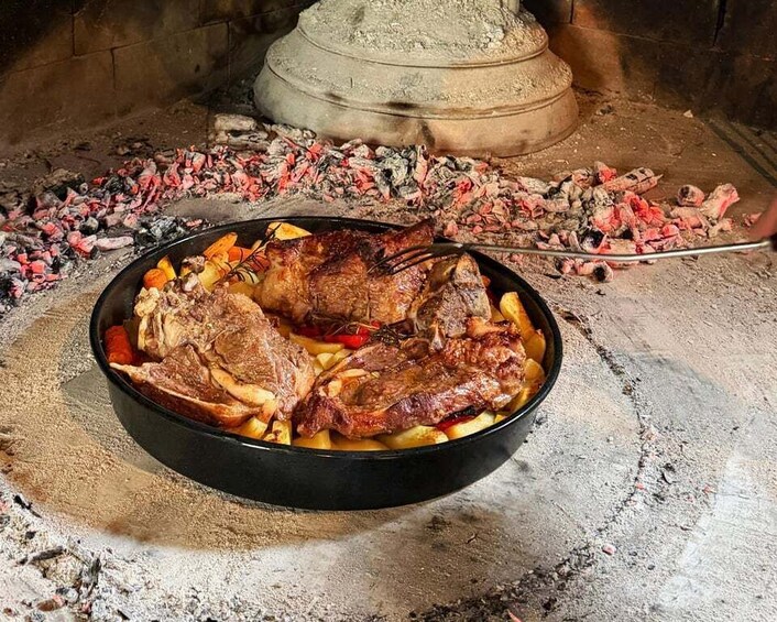 A roasted meat dish on a skillet with charred coals underneath. 3