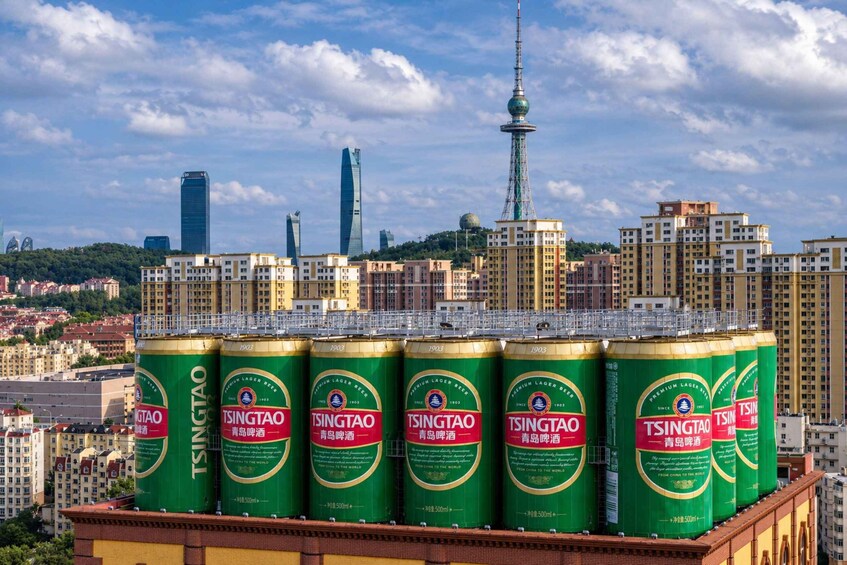 A row of Tsingtao beer cans on a rooftop with a cityscape in the background. 5