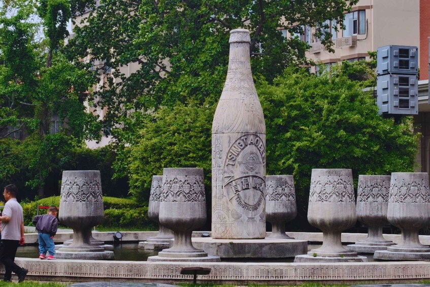 A park with a decorative fountain featuring a tall, narrow vase and ornate urns. 4