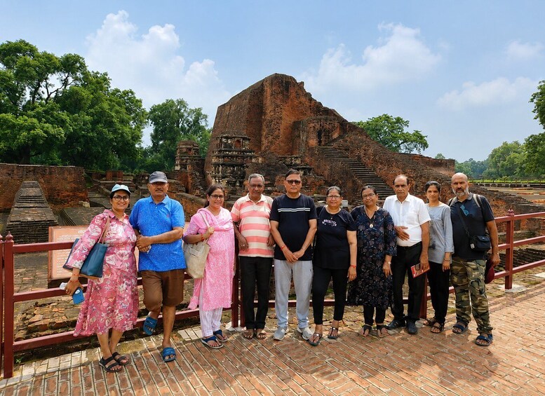 A group of people standing in front of ancient ruins with a clear sky. 1