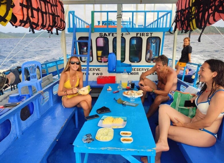 A group of people on a boat with life jackets, a table with food, and a sign that reads 'SAFETY FIRST.' 5