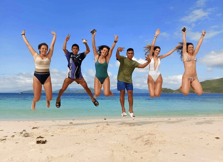 A group of people jumping on a beach with clear skies and calm sea. 4