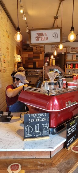 A coffee shop interior with a vintage espresso machine, a menu board, and a wall with a clock. 4