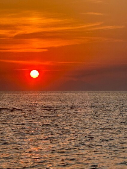 A sunset over a calm sea with a visible sun near the horizon. 3
