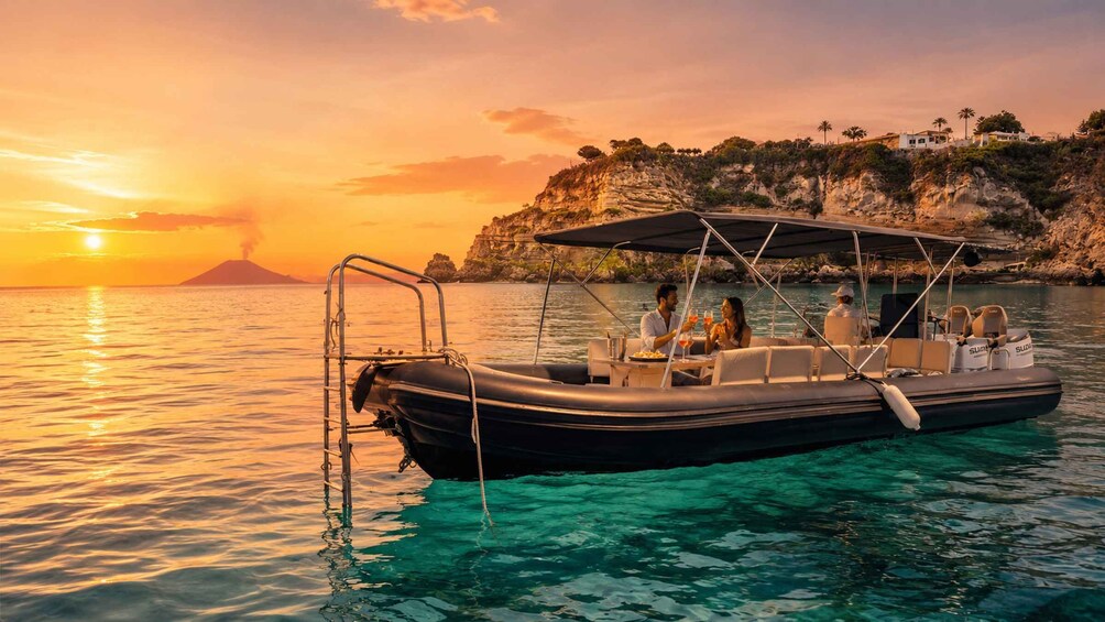 A boat with passengers enjoying a sunset by a rocky coastline. 1