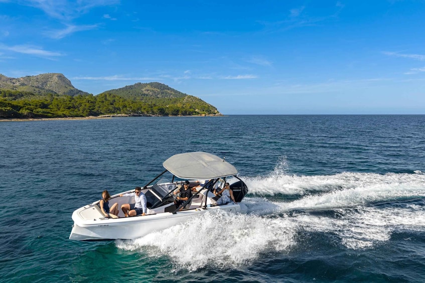 A white motorboat with a canopy, speeding across a calm sea with a mountainous coastline in the background. 1