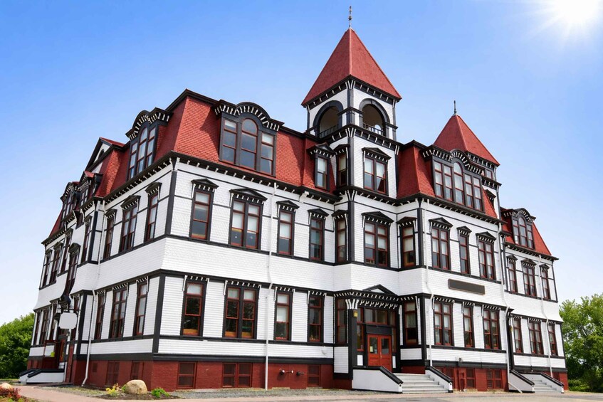 A large, historic building with a red roof and white walls, featuring multiple towers and arched windows. 3