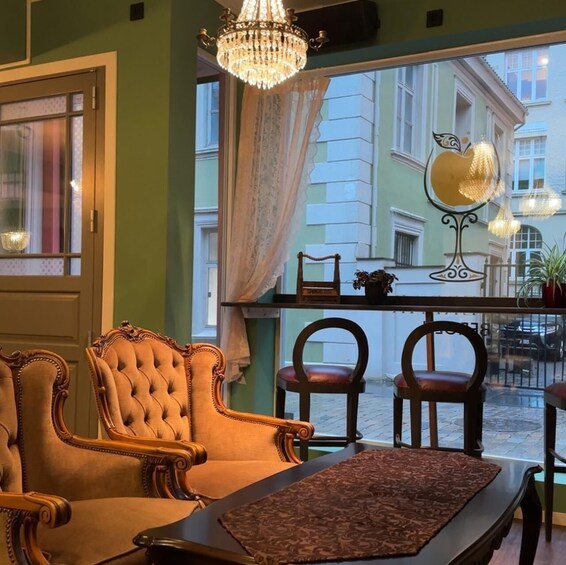 A cozy room with ornate chairs, a table, and a view of a street with buildings. 5