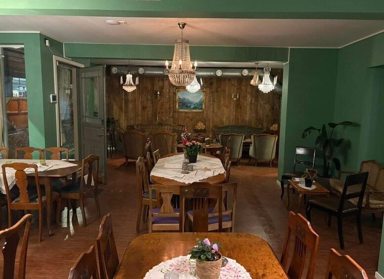 A dining room with wooden furniture, a chandelier, and a green wall. 1