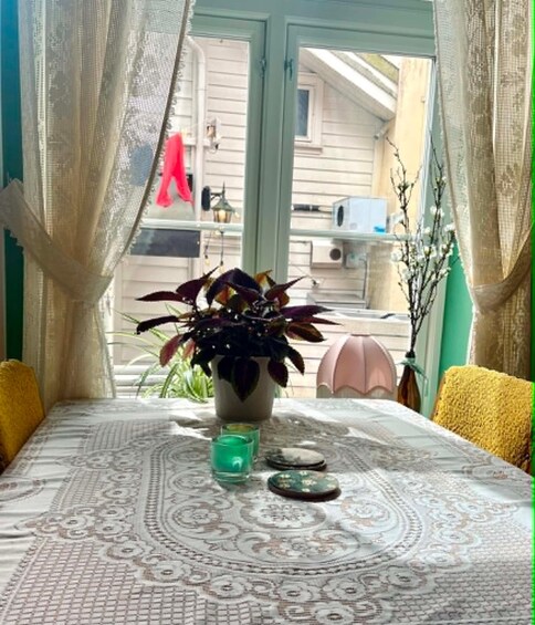 A table with a patterned tablecloth, a potted plant, a green candle, and decorative stones. 4