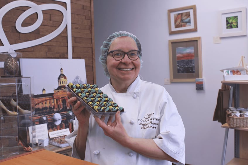 A person in a white chef's coat holding a tray of heart-shaped chocolates. 1