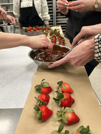 People dipping strawberries into melted chocolate. 3