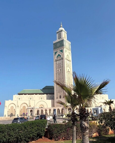 A large mosque with a tall minaret, arched doorways, and a green roof. 3