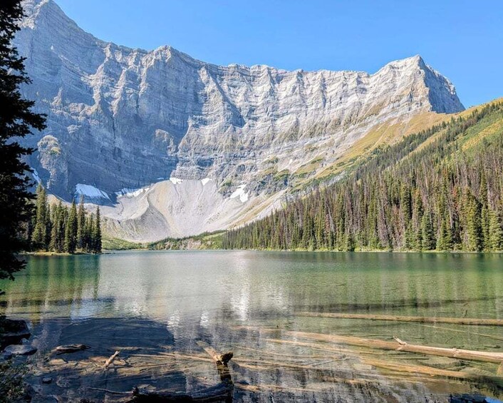 A mountain lake with clear water, surrounded by forest and a prominent mountain peak. 4