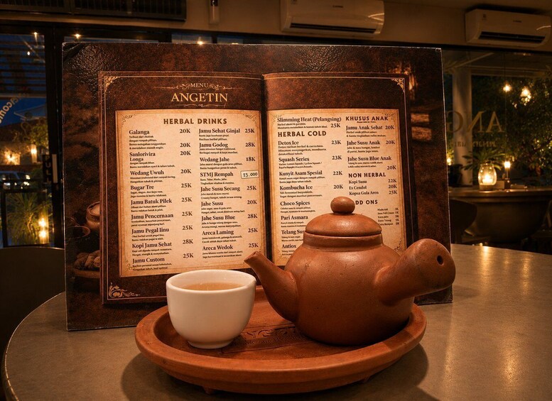 A menu board titled 'ANGETIN' with sections for 'HERBAL DRINKS' and 'HERBAL COLD,' a teapot, and a cup on a table. 2
