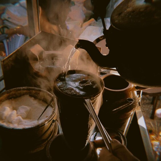 A steaming pot being filled with water, surrounded by various kitchen utensils and containers. 3
