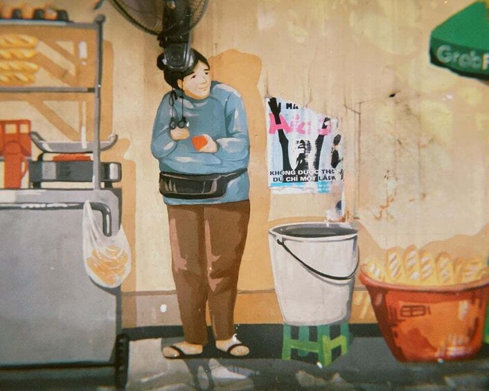 A person standing next to a bucket and a bag, with a wall in the background. 1