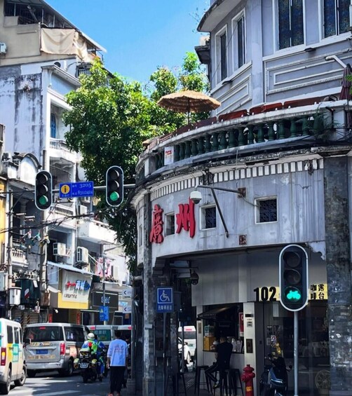 A street with a building labeled '102' and a traffic light displaying a green light. 5
