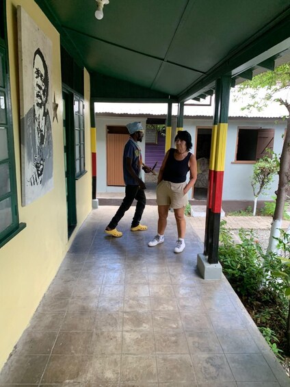 A covered walkway with tiled flooring, a mural on the wall, and a building with a purple door in the background. 4