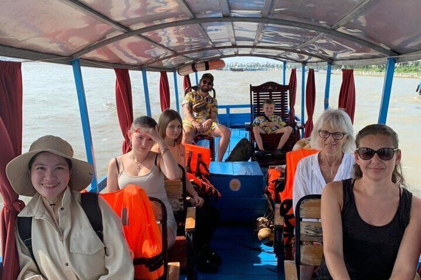 A group of people on a boat with life jackets and a covered upper deck. 5