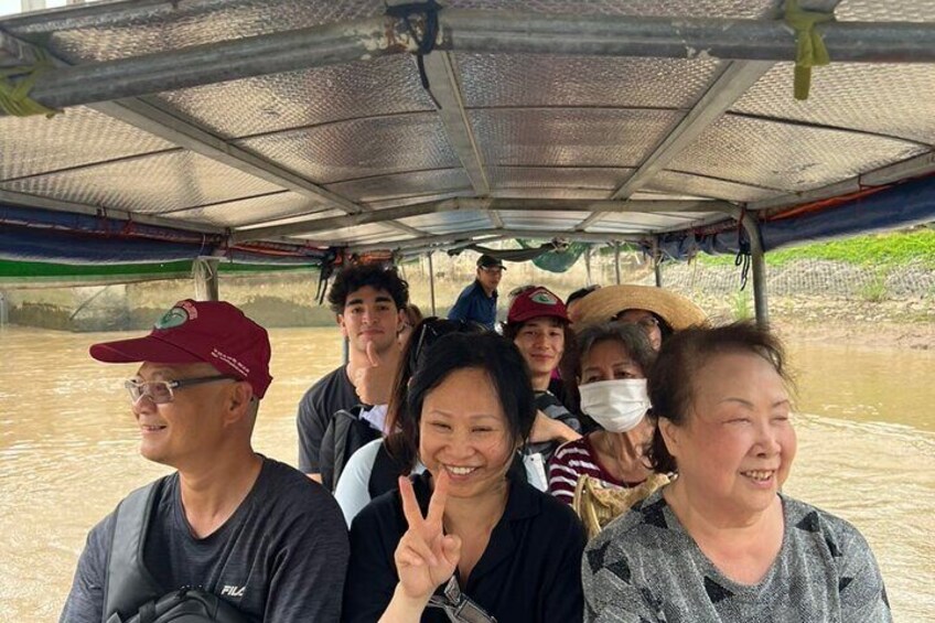 A group of people on a boat with a metal roof, surrounded by water. 3