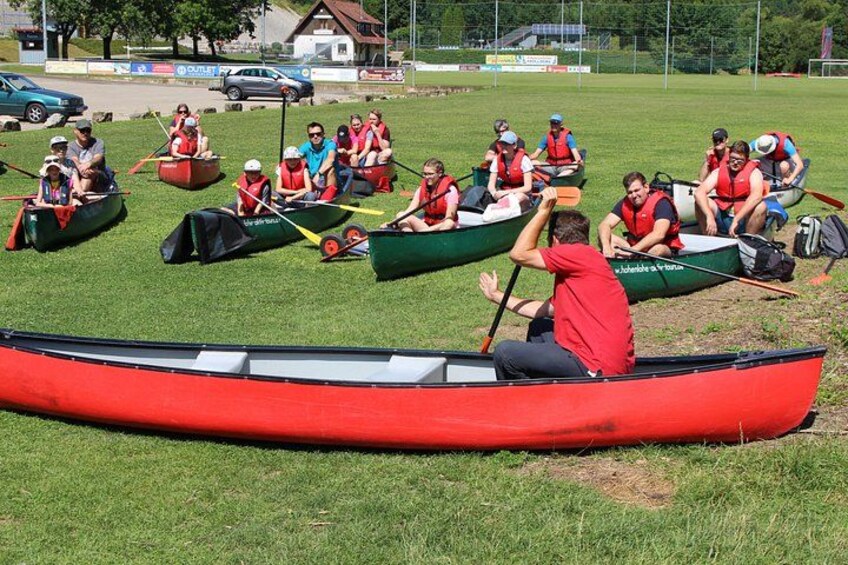A group of people in canoes on a grassy field. 5