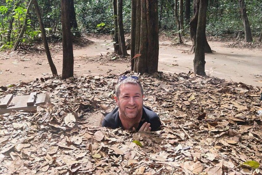 A person lying on the ground surrounded by dry leaves in a forested area. 3