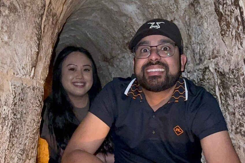 Two people inside a cave with rocky walls. 1