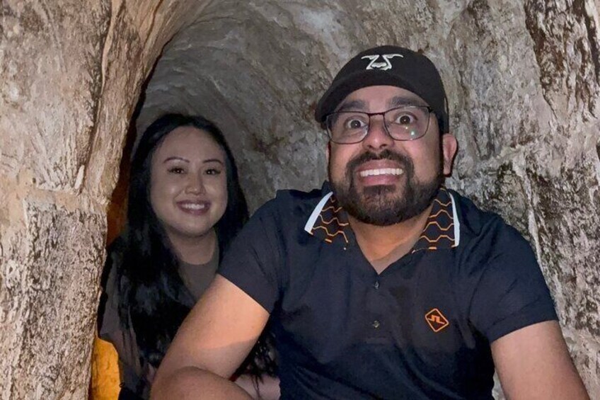 Two people inside a cave with rough, natural rock walls. 1