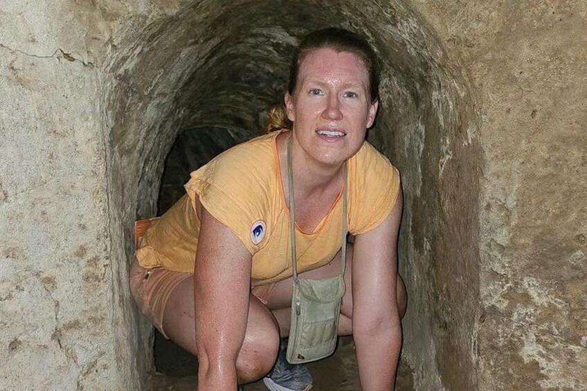 A person crouching inside a stone tunnel. 2
