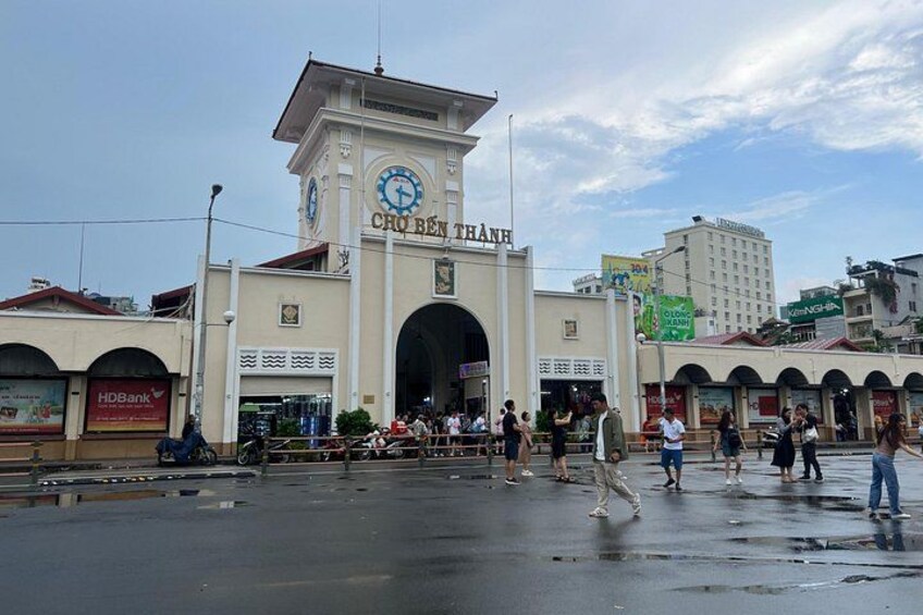 A historic building with a clock tower, a large archway, and a wet street. 3