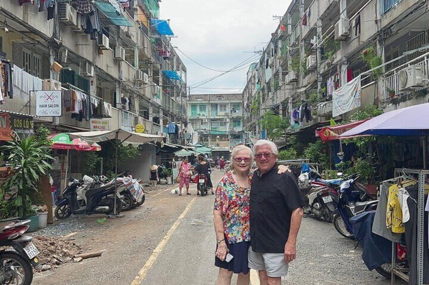 A narrow street with buildings on either side, some with signs, and a few motorcycles parked along the road. 4