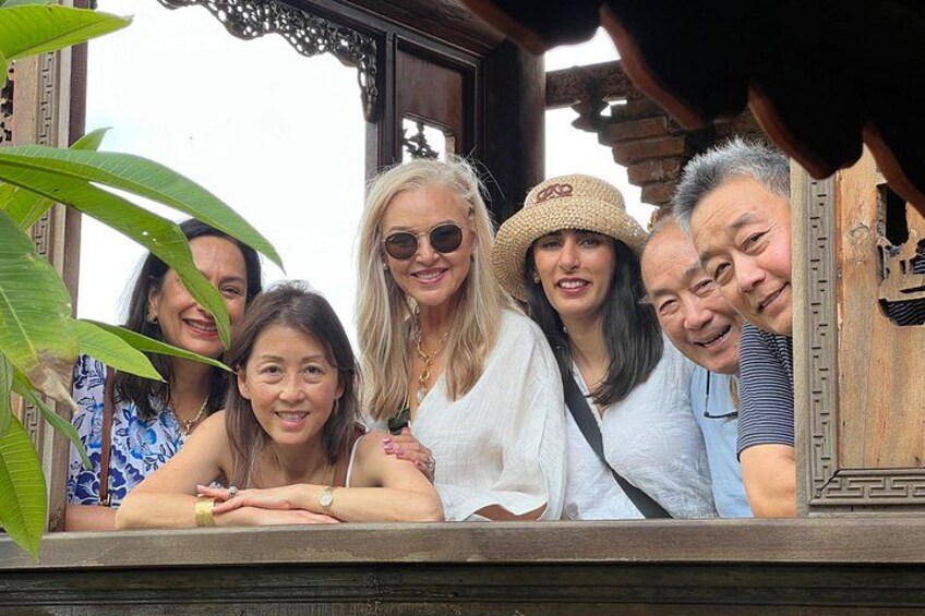 A group of people posing in front of a wooden structure with intricate carvings. 2