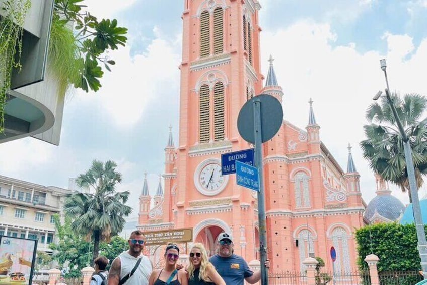 A pink church with a clock, palm trees, and a sign for Duong Building. 5