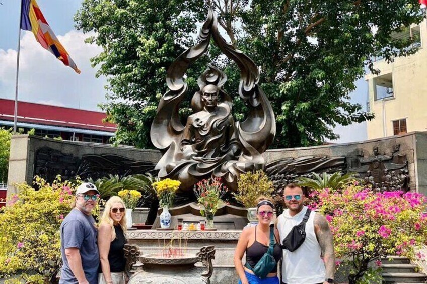 A group of people posing in front of a bronze statue with a flag in the background. 4
