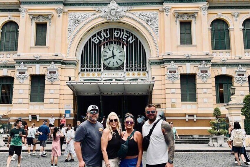 A group of people in front of a building with a large clock and the sign 'BUON DIEV'. 5