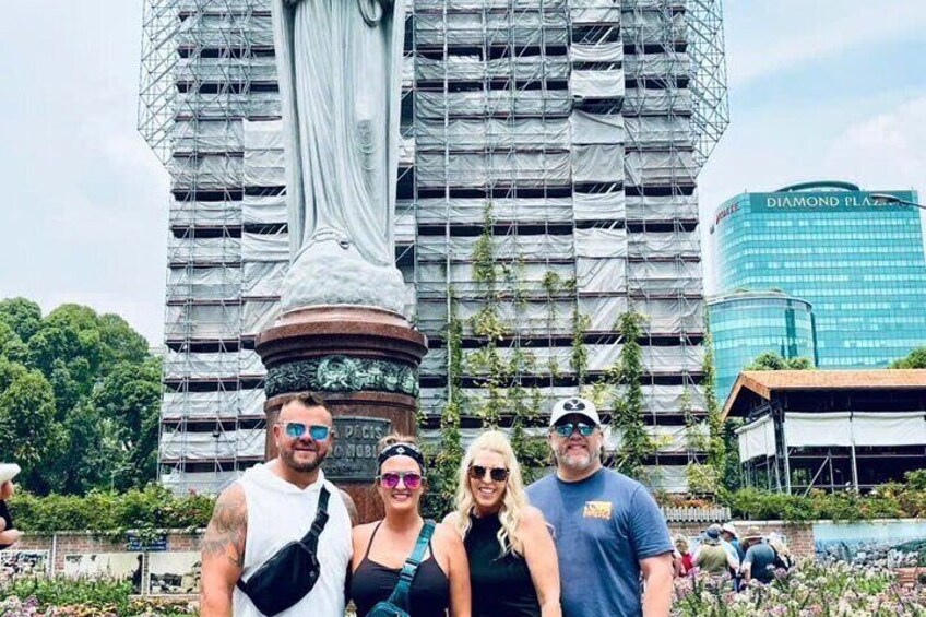 A group of people standing in front of a statue with a building in the background. 4