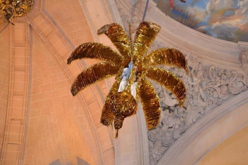 A golden, star-shaped chandelier in a grand room with ornate ceiling details. 5