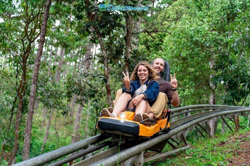 Two people on a wooden roller coaster track surrounded by trees. 1