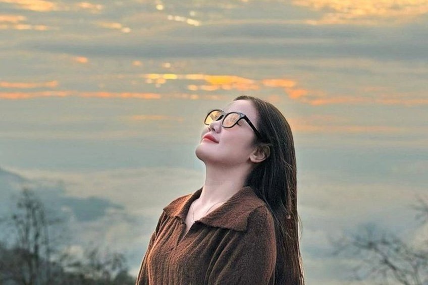 A person standing outdoors with a mountainous landscape in the background. 5