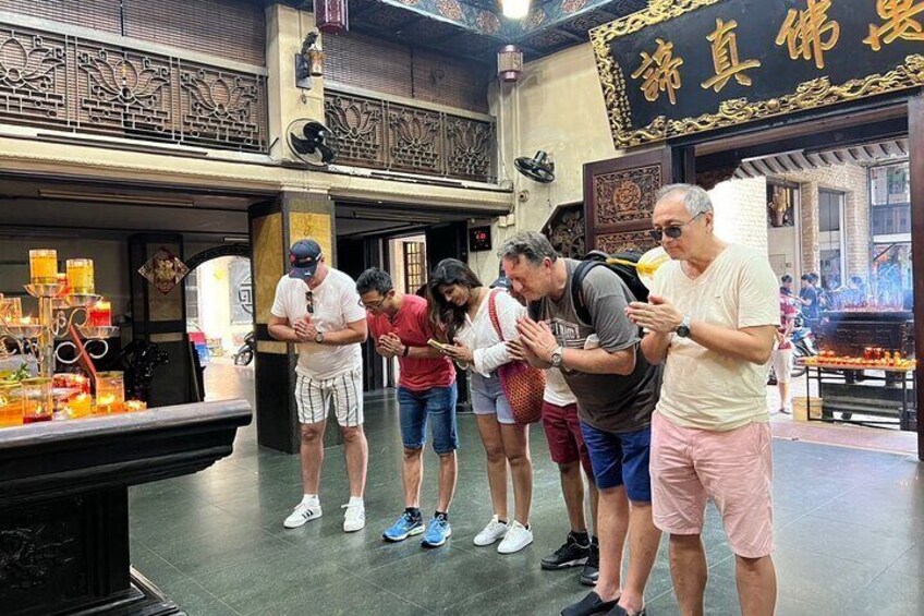 A group of people standing in a traditional market with ornate railings and a sign with Chinese characters. 4