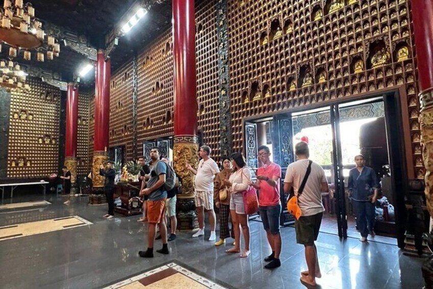 A group of people inside a temple with ornate walls and red pillars. 5