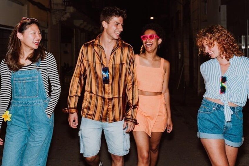 Four people walking on a street at night. 3