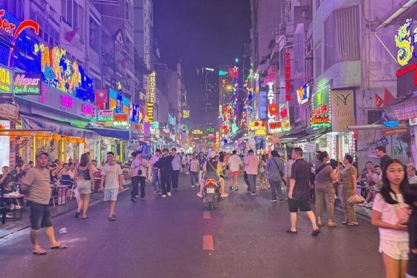 A busy street lined with brightly lit shops and restaurants. 2