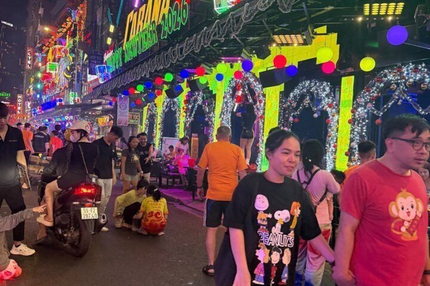 A crowded street with neon signs and festive decorations. 3
