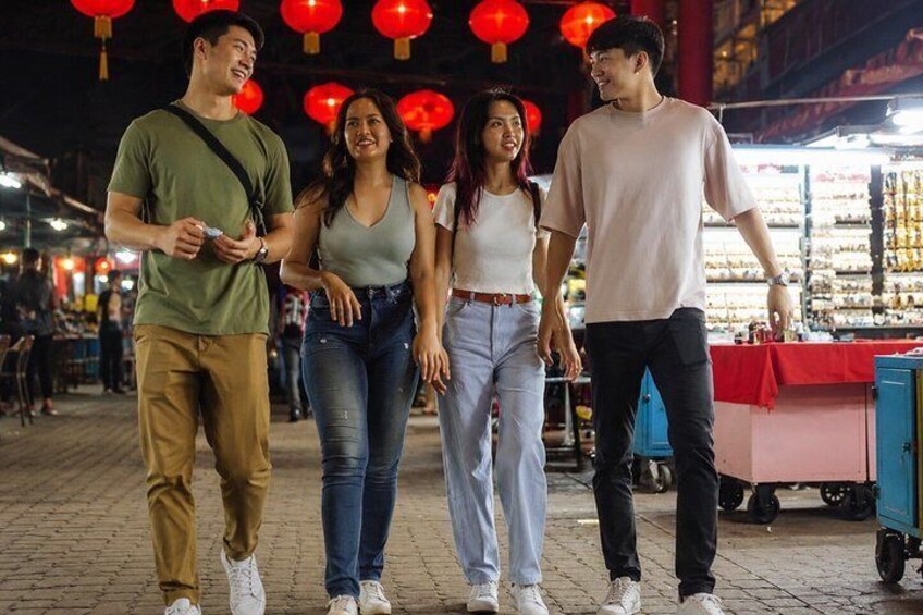 A group of people walking in an outdoor market area with red lanterns overhead. 4