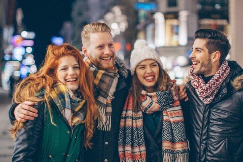 A group of people in winter clothing, standing on a city street at night. 5