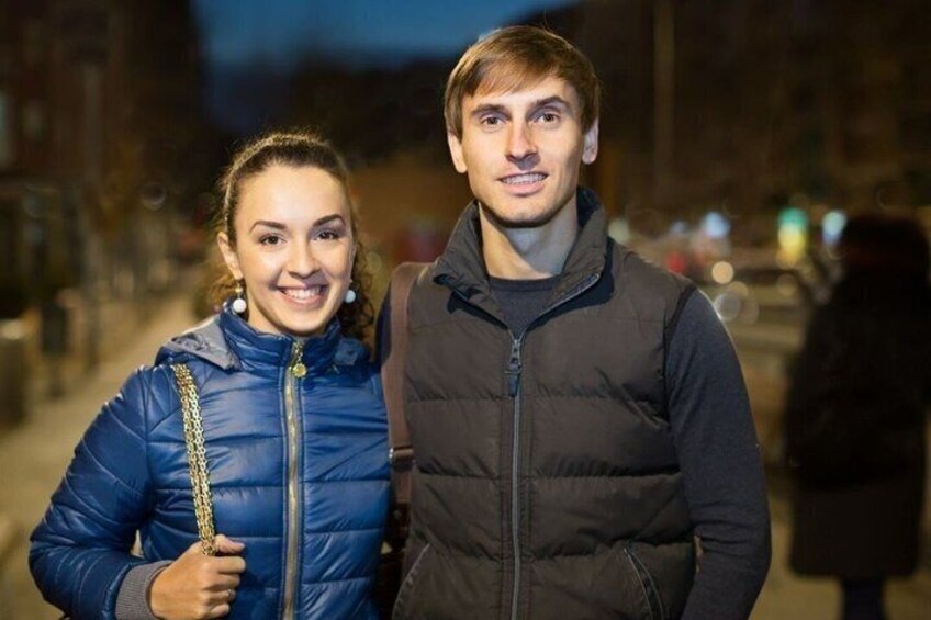 Two people standing on a city street at night. 2