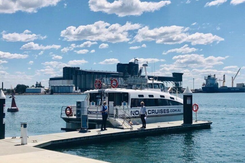 A white boat docked at a pier with a 'NO CRUISES' sign, a lifebuoy, and a person standing on the dock. 5